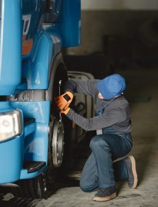 A young worker checks wheel. Truck malfunction. Service work.
